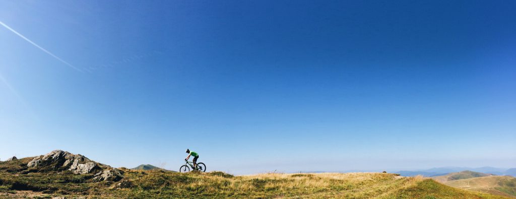 Titelbild - Mountainbiker fährt alleine in den Bergen